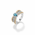 Silver ring with blue gemstone and gold accents on a white background
