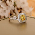 Ring with a yellow gemstone and diamond accents on a neutral background